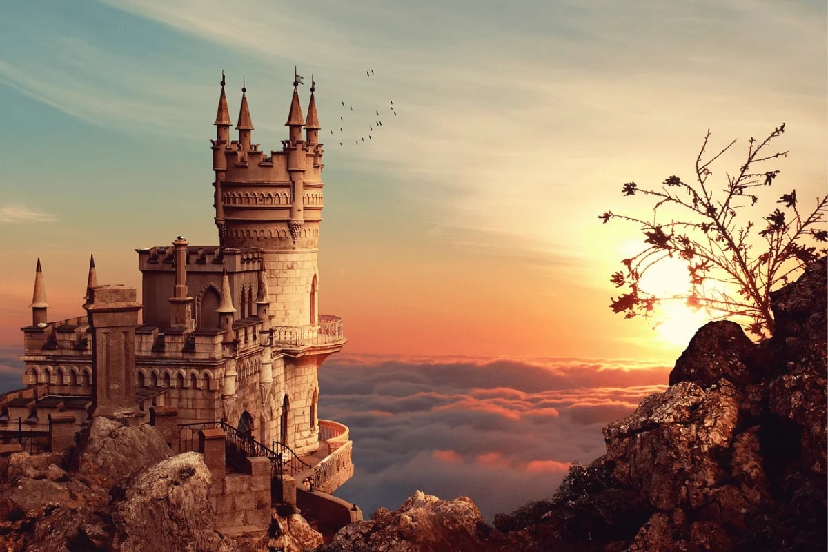 A majestic stone castle with tall spires sits atop a rocky cliff, surrounded by clouds and a vibrant sunset sky.